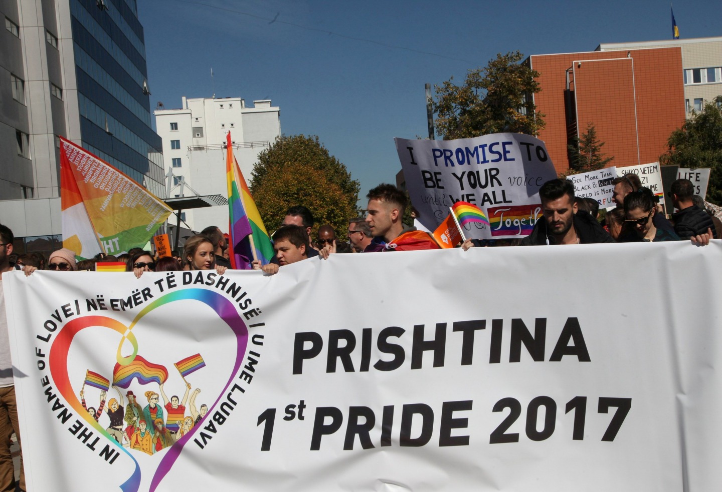 Kosovon ensimmäiseen pride-paraatiin osallistuneet liehuttivat sateenkaarilippuja Pristinan keskustassa (kuva: Hazir Reka / Reuters / Lehtikuva)